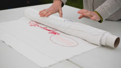 A large fabric art work shows stitched writing reading "An Idea Shopping List"