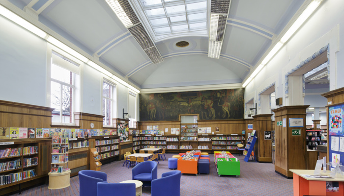 Spacious and colourful children's area There are tables and chairs in the middle of the area, wood panelling a third of the height of the walls and a high curved ceiling with a long rectangular, colonial-style skylight. From this angle you can see the mural of 'Queen Mary at the Battle of Langside'