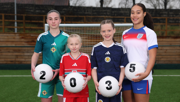 Four female footballers wearing green, red, blue and white tops hold footballs which spell out '2035'