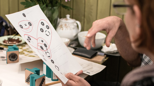 Two people sit at a table looking at an artistic mapping project.