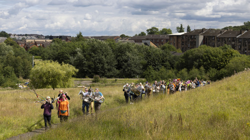 A group of people march as part of a celebratory parade through Cowlairs.