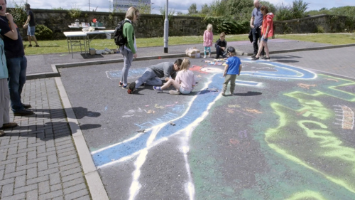 Children draw on the car park with chalk.