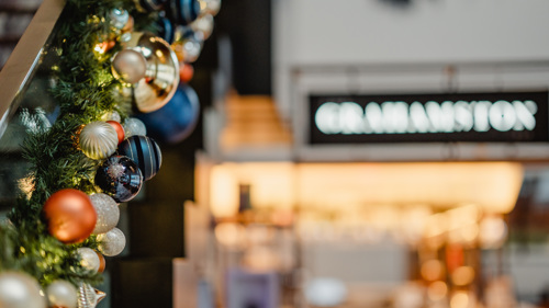 Close up of amber and navy baubles on a wreath with The Grahamston restaurant blurred in the background.
