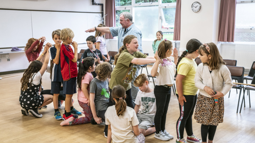 An drama director instructors children in a movement excise. 