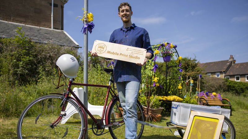 A person stands next to a bike smiling. 