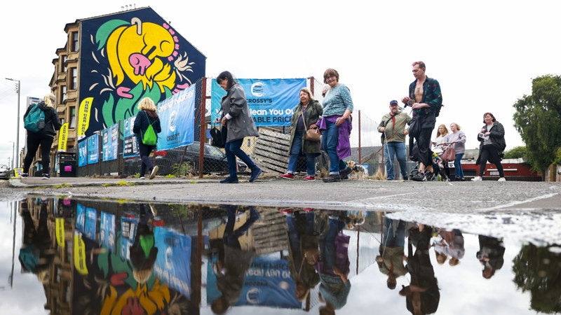 A group of people follow the Govan Mural Trail